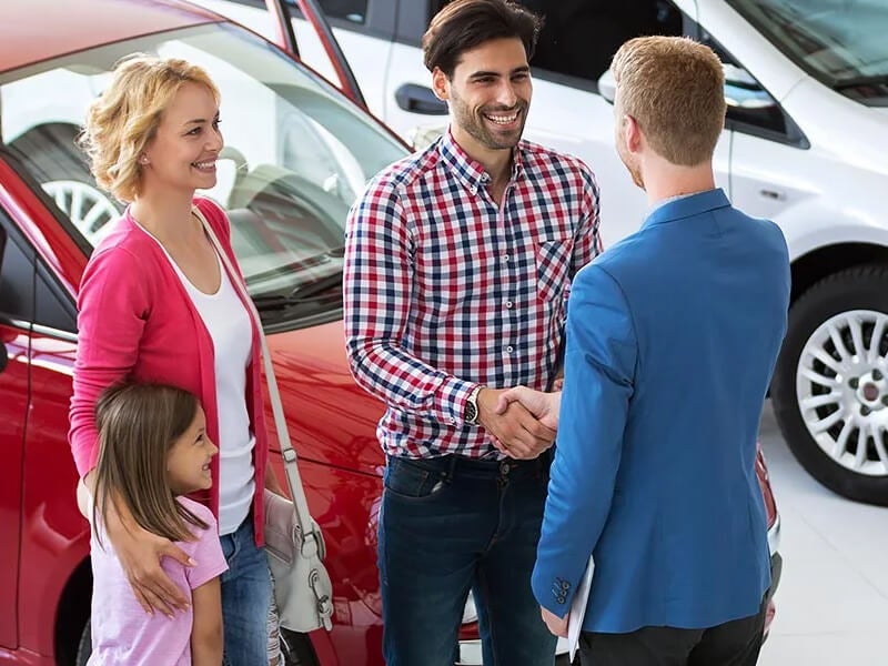 Dealership employee talking to customer and their family